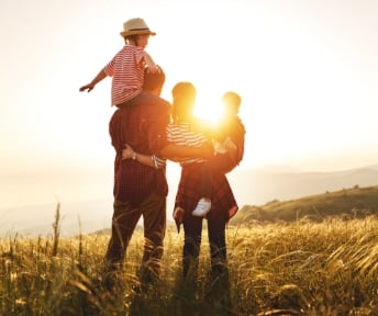 A family standing on a hill facing the sun 
